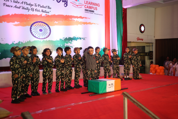 Students dressed in camouflage uniforms performing a patriotic skit on stage at The Learning Campus for Independence Day.