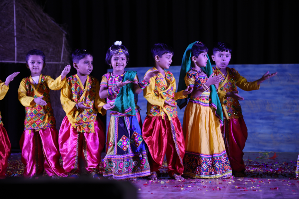 A young preschooler performing on stage in a traditional pink costume at a cultural event in Ravet.