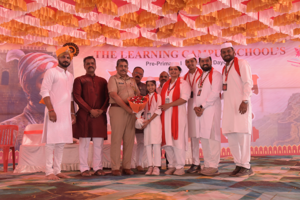 A young student presenting a flower bouquet to a police official on stage at The Learning Campus School's event.