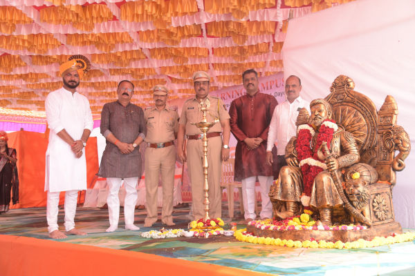 Dignitaries and police officials standing near a golden Chhatrapati Shivaji Maharaj statue during a school ceremony at The Learning Campus.
